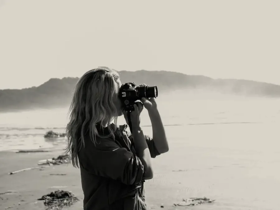 A woman taking a photograph on a misty beach
