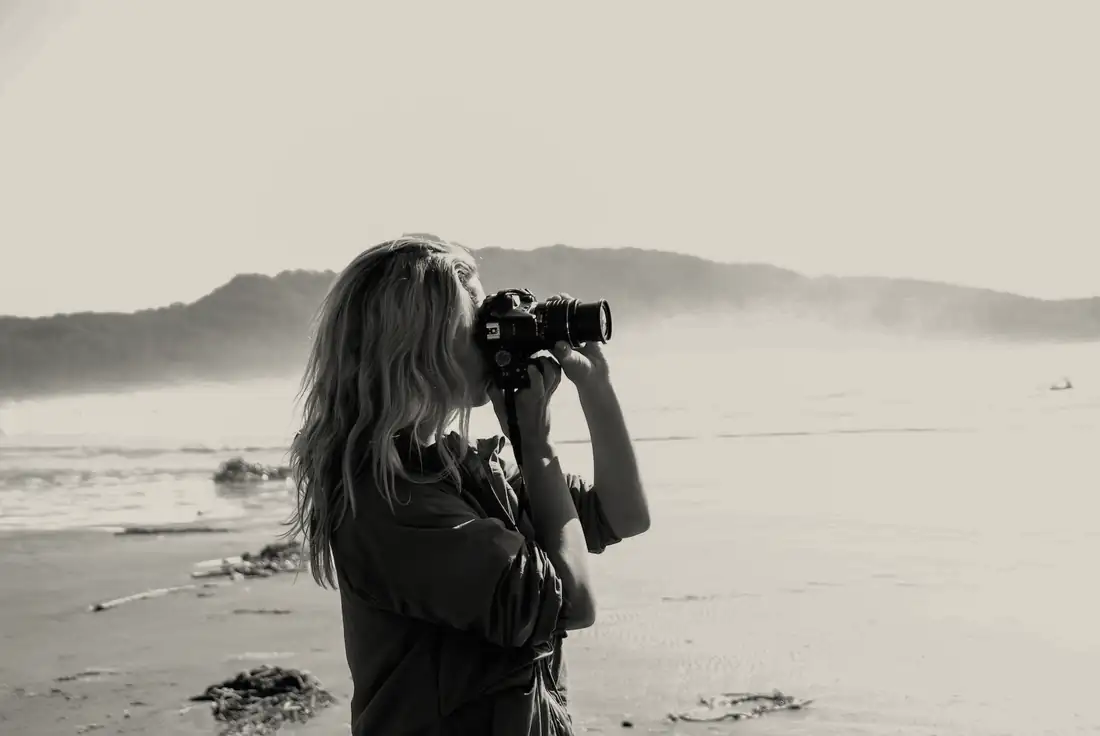 A woman taking a photograph on a misty beach