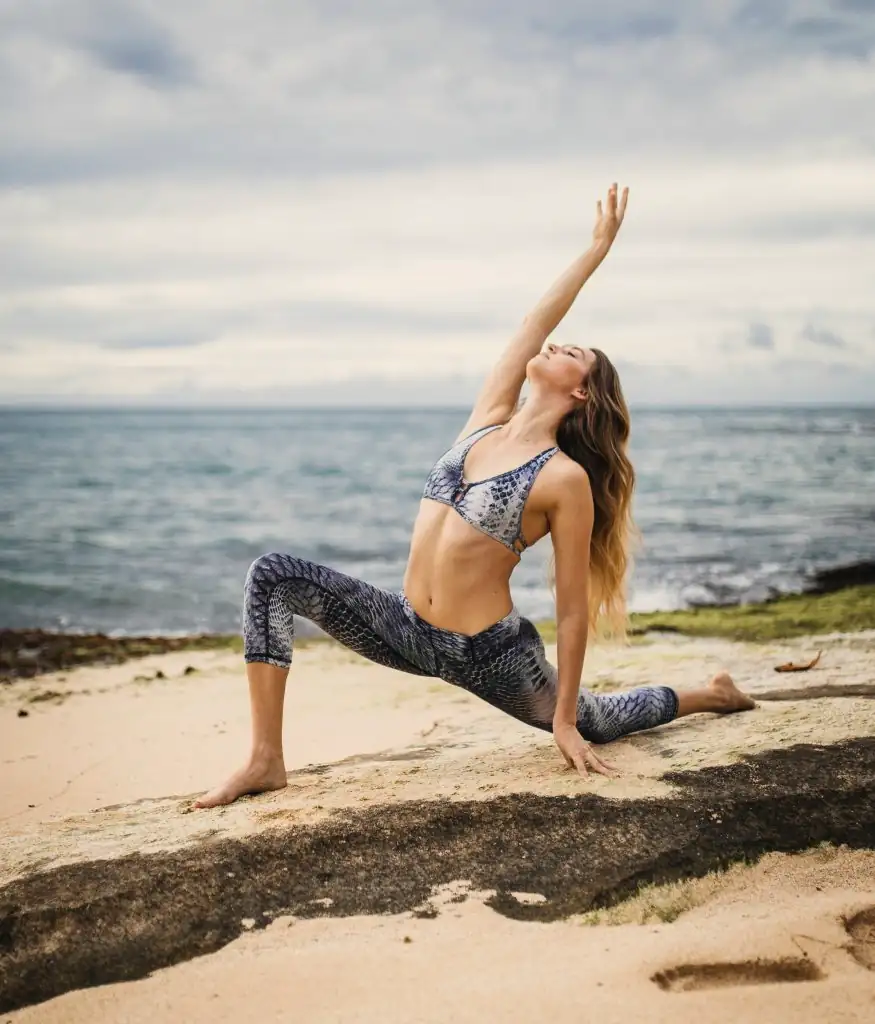 A woman stretching in a yoga pose on a beach