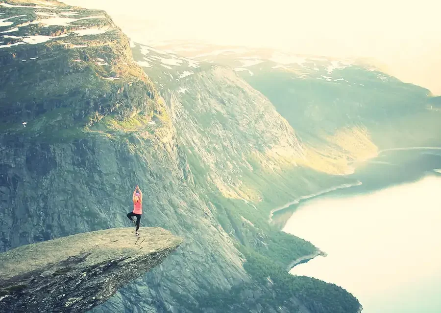 A person standing on a cliff above a fjord