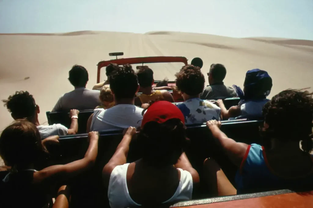 Travellers in an open vehicle crossing sand dunes