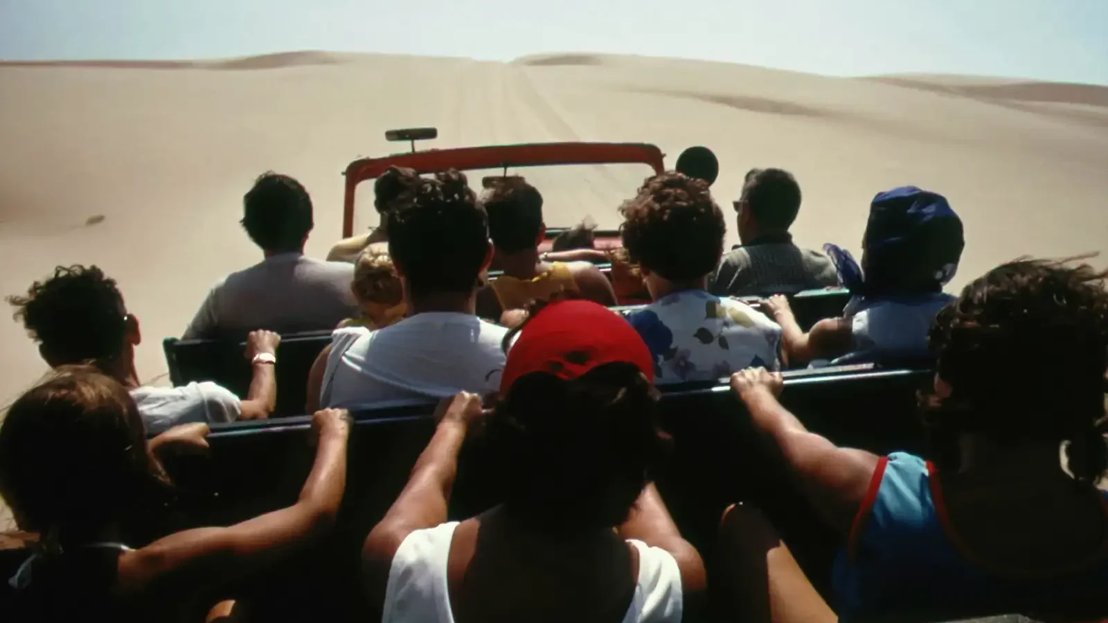 Travellers in an open vehicle crossing sand dunes