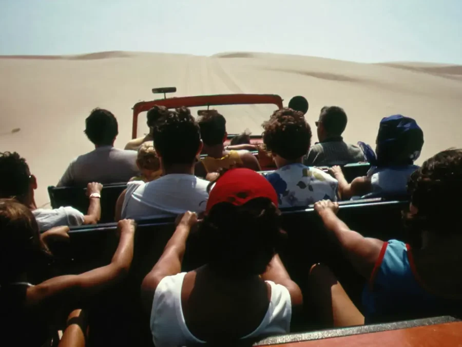 Travellers in an open vehicle crossing sand dunes