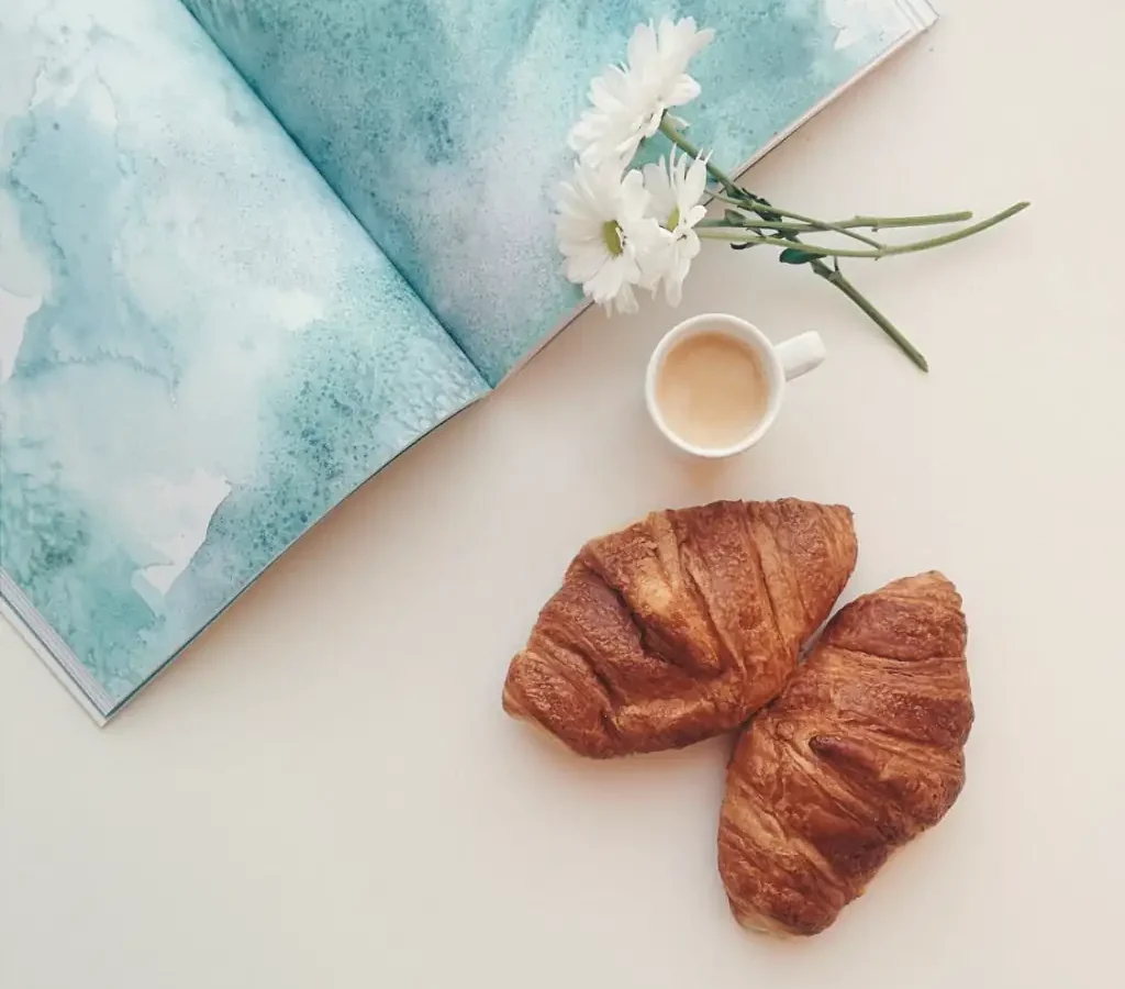 A map, coffee and croissants on a white table