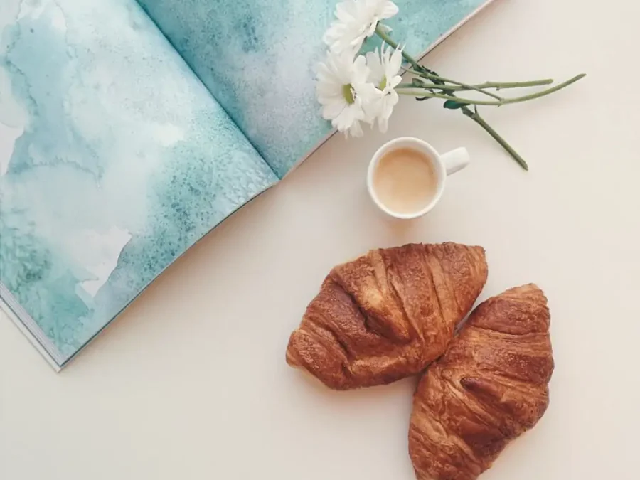 A map, coffee and croissants on a white table