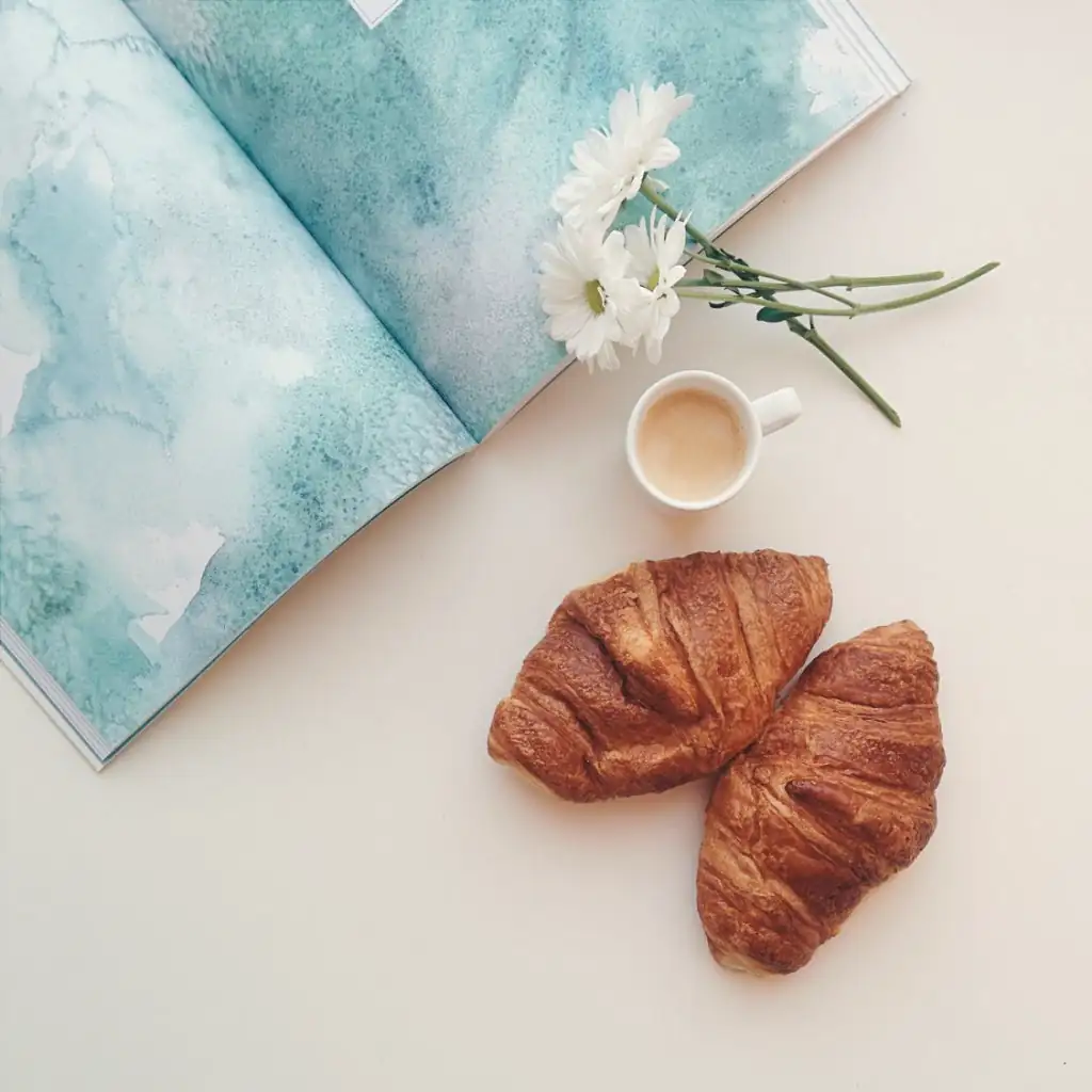 A map, coffee and croissants on a white table