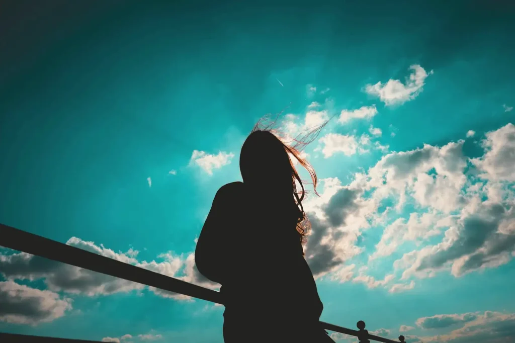 Silhouette of a woman against a blue sky with clouds