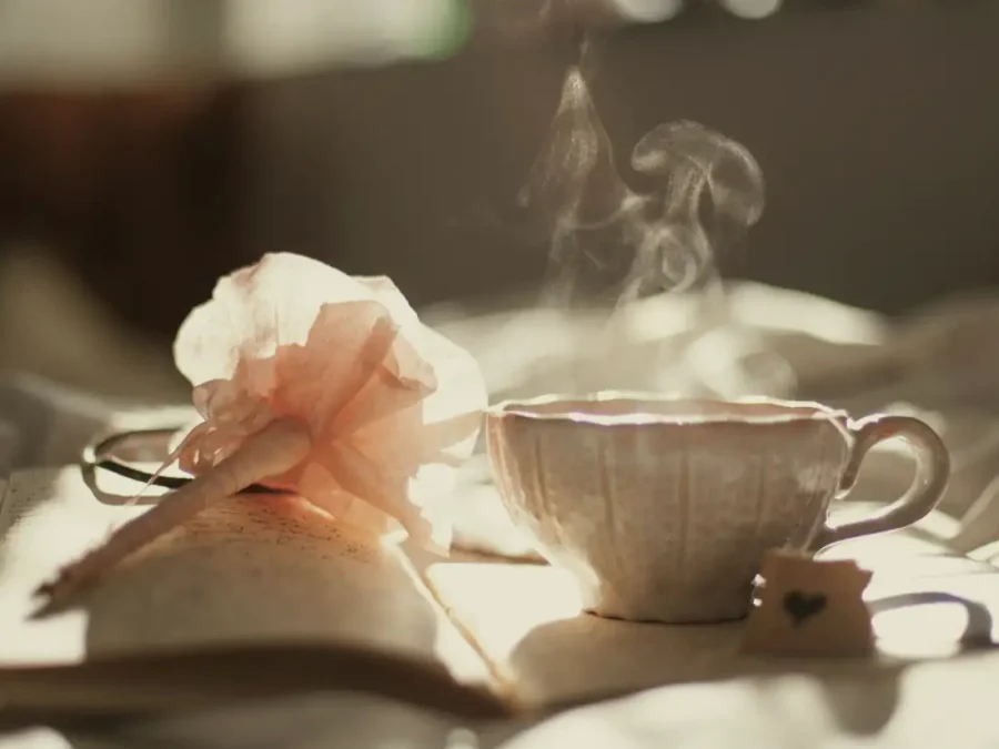 A steaming cup of tea beside an open book